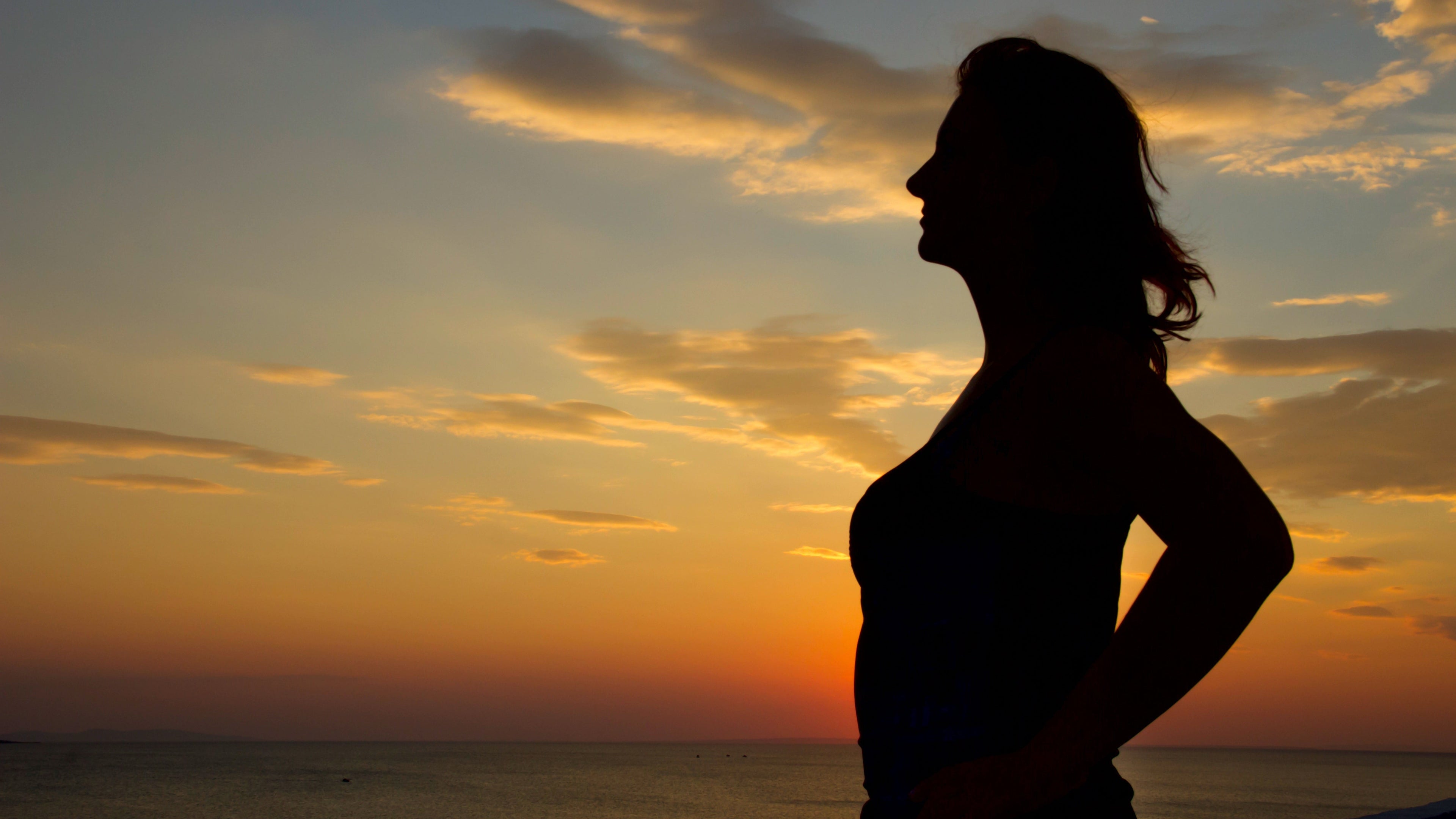Silhouette of a woman against a sunset sky